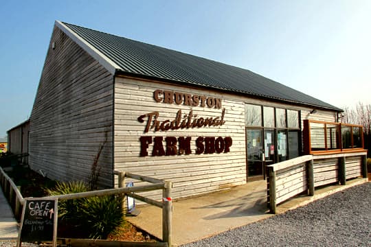 The timber-clad Churston Traditional Farm Shop building, with the café-open board by the gate